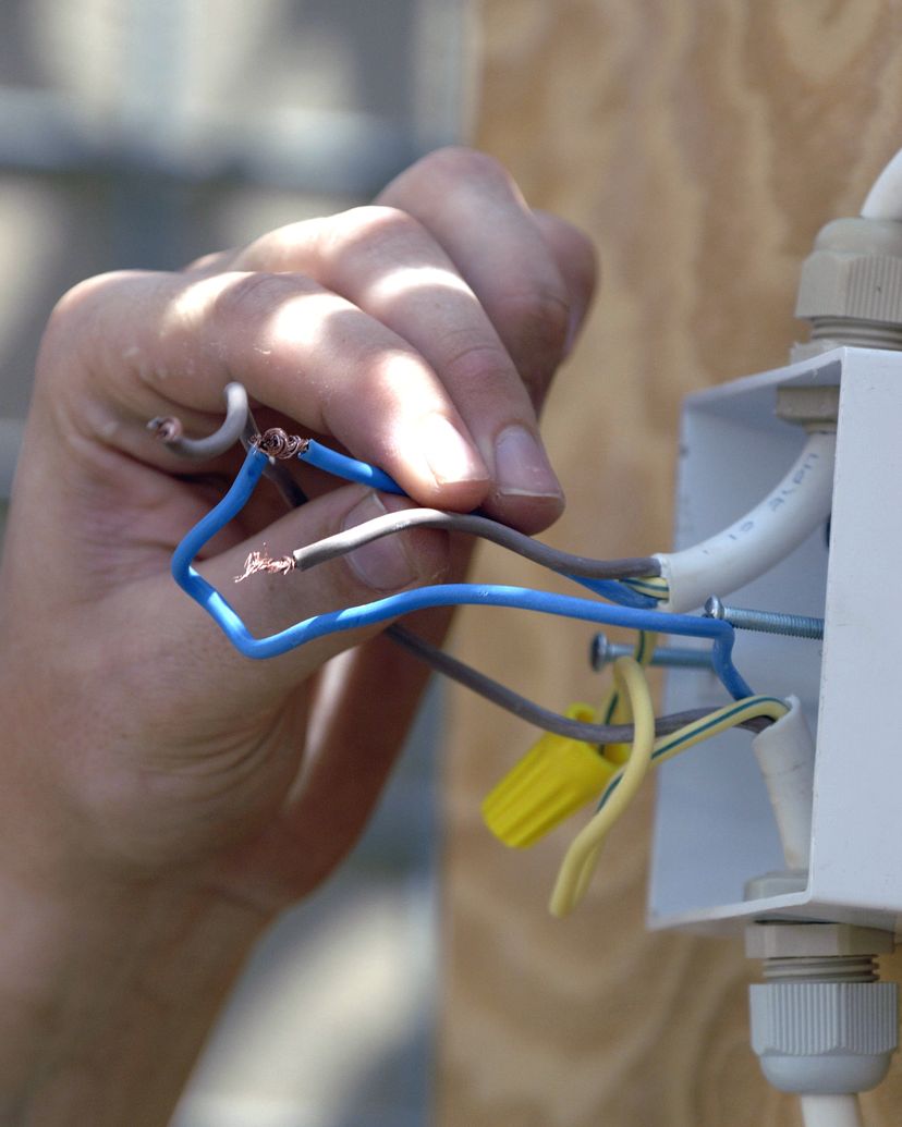Dłoń łącząca przewody w natynkowej puszce elektrycznej